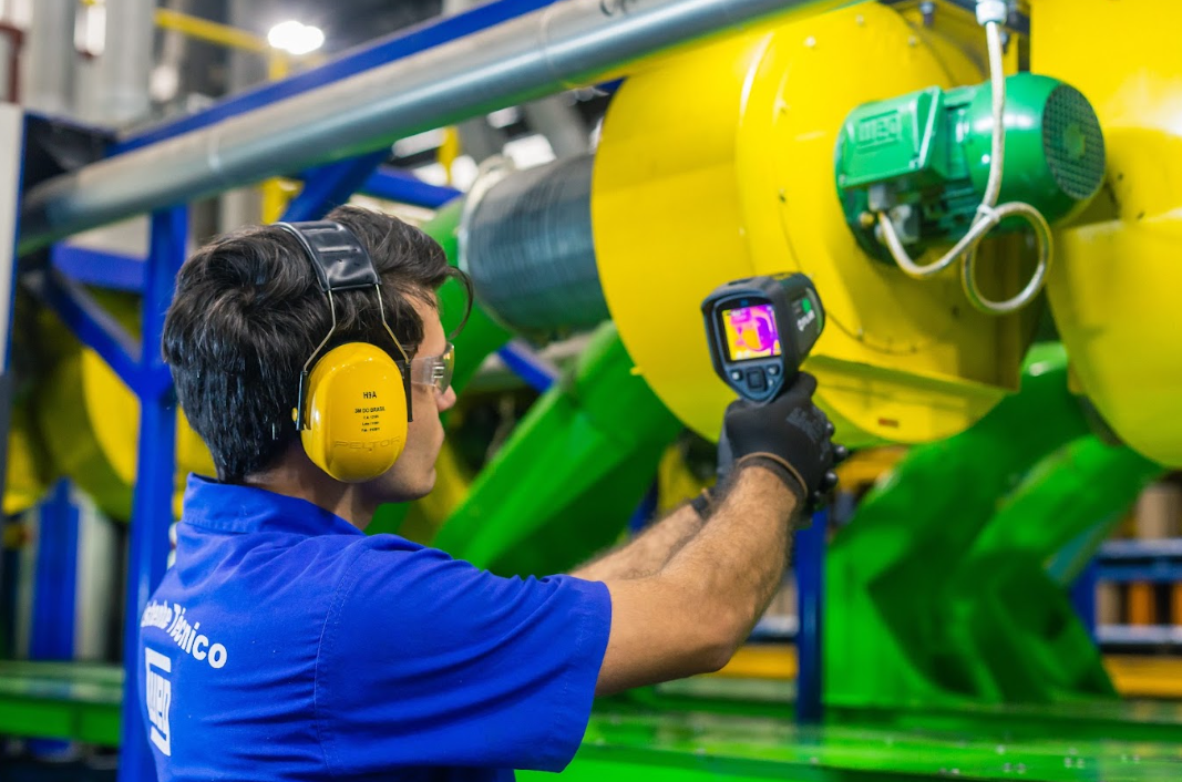 Technician using thermal imaging test equipment on an AC motor to verify performance after motor repair.
