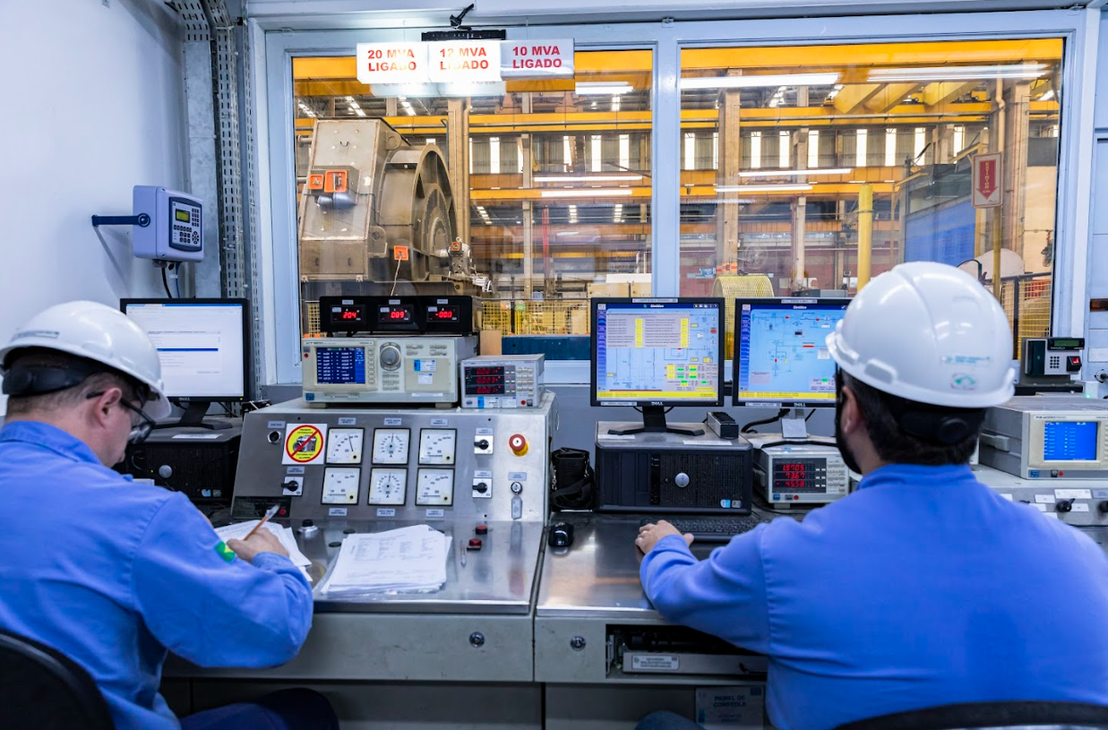Engineers in a control room monitoring electric motor performance and temperature data through industrial automation systems.