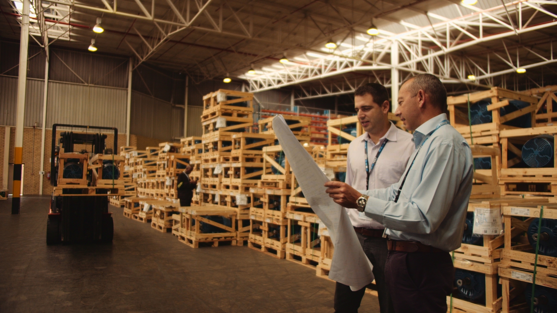 Warehouse managers discussing inventory with crate electric motors in the background.