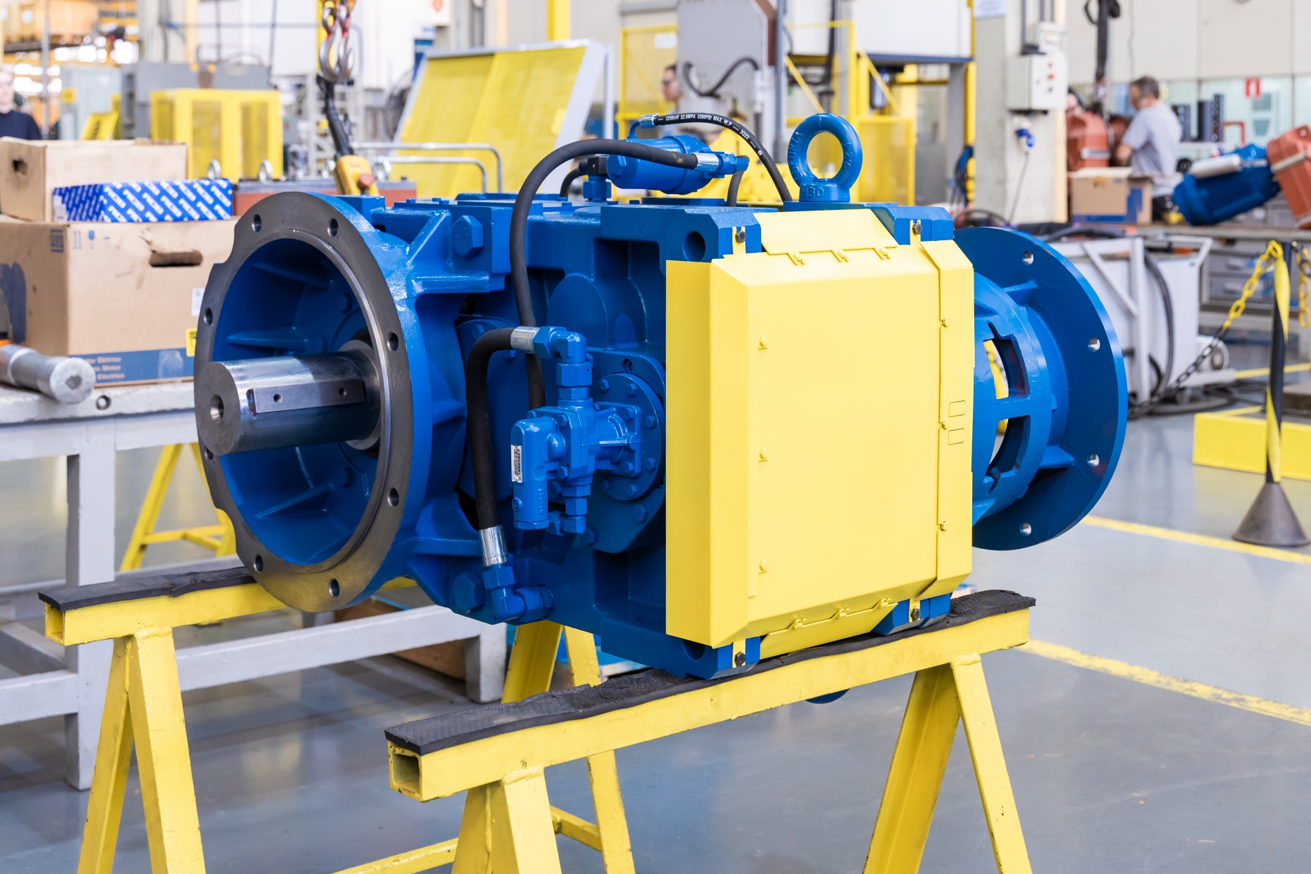 Close-up of an industrial electric motor with hydraulic components on a factory floor used in industrial applications.