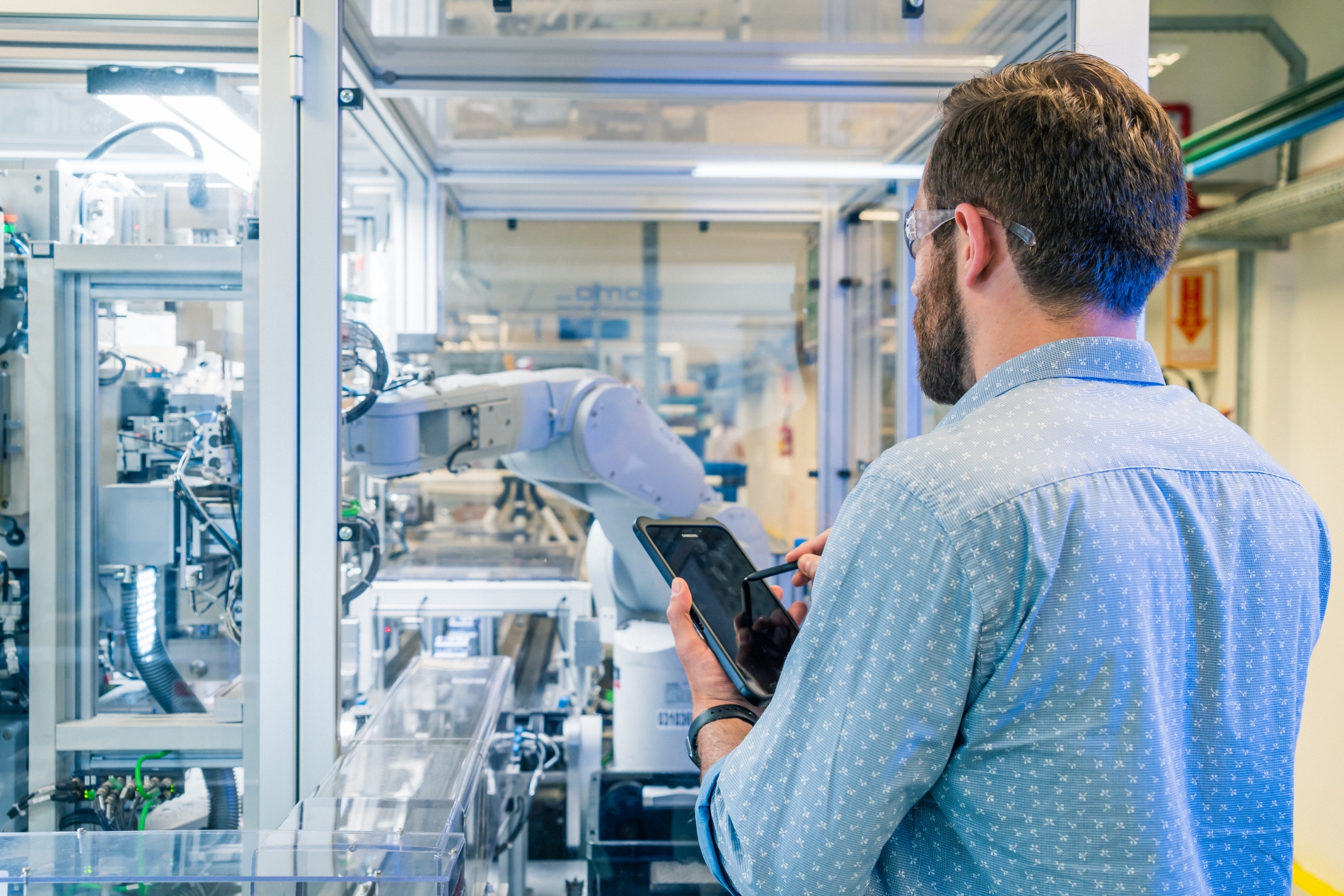 An engineer monitors industrial automation equipment in a smart manufacturing facility using electric control systems.