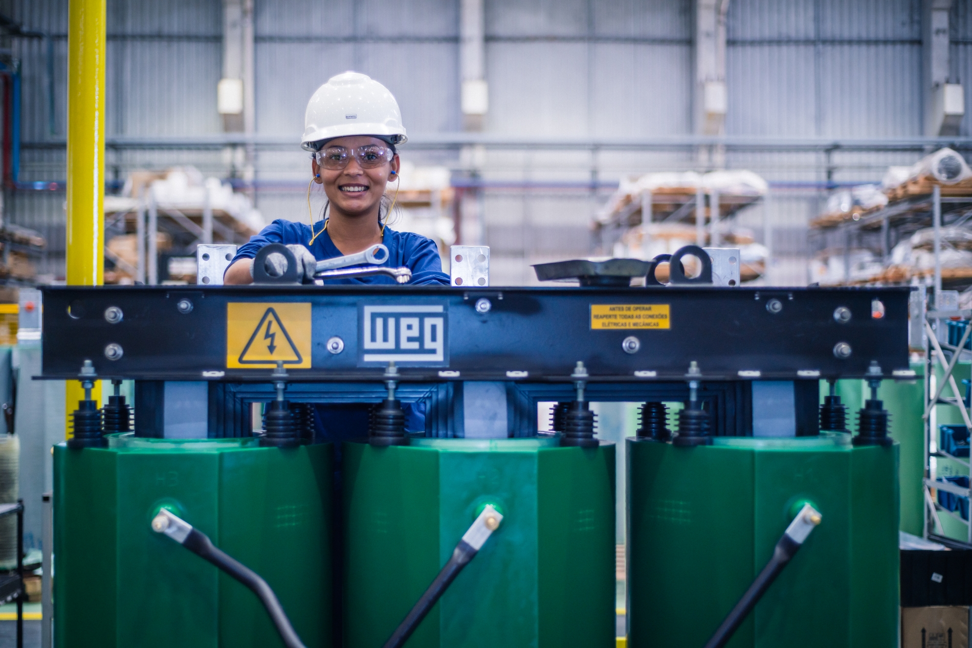 Technician wearing safety gear working with WEG equipment in a manufacturing facility, highlighting industrial automation in action.