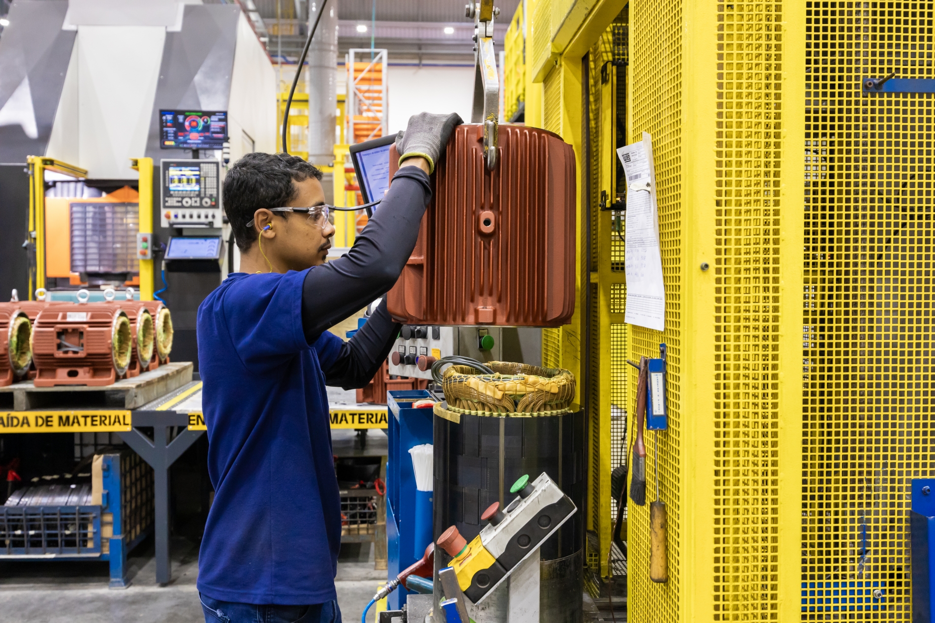 Technician performing maintenance on a large electric motor inside a manufacturing plant, emphasizing reliability in OEM motor applications.