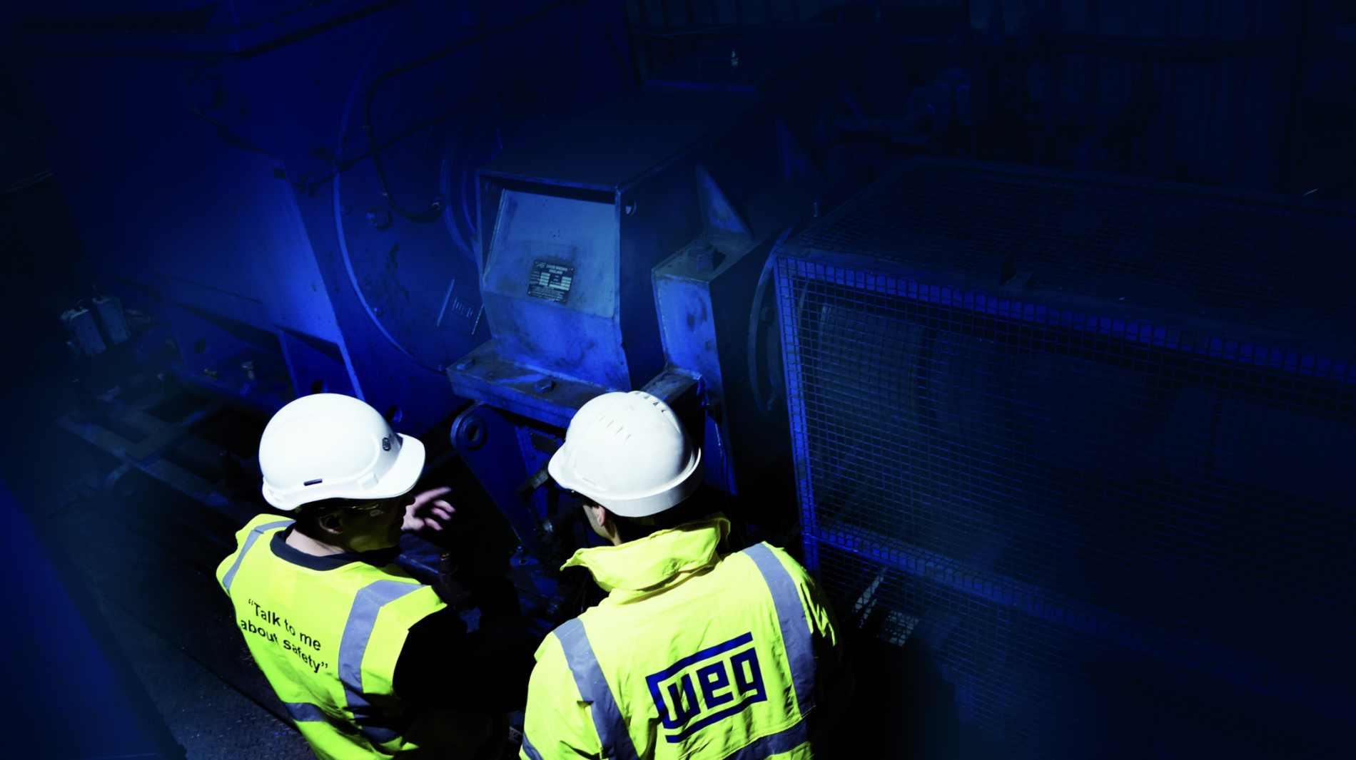 Technicians inspecting industrial machinery powered by WEG electric motors in a dimly lit facility.