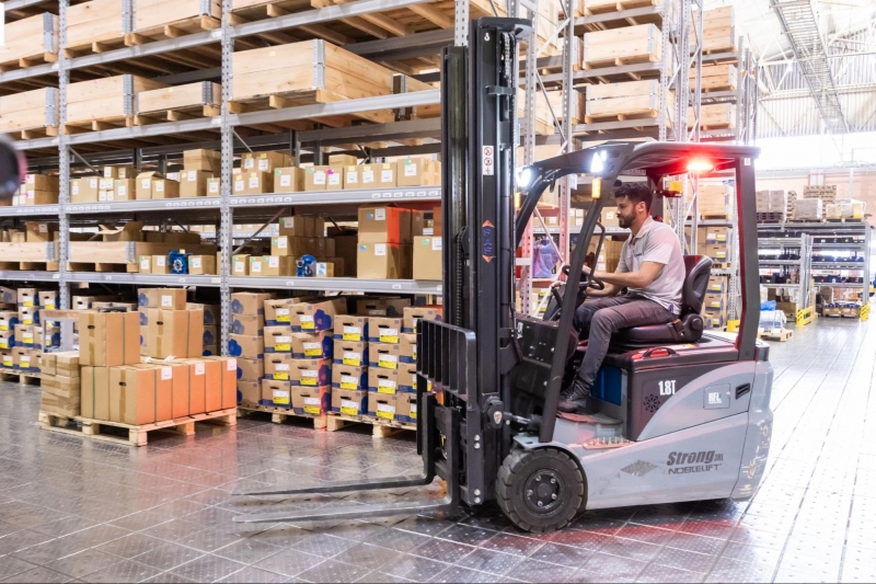 A technician operating a forklift in a warehouse, demonstrating typical warehouse operations and industrial automation processes.