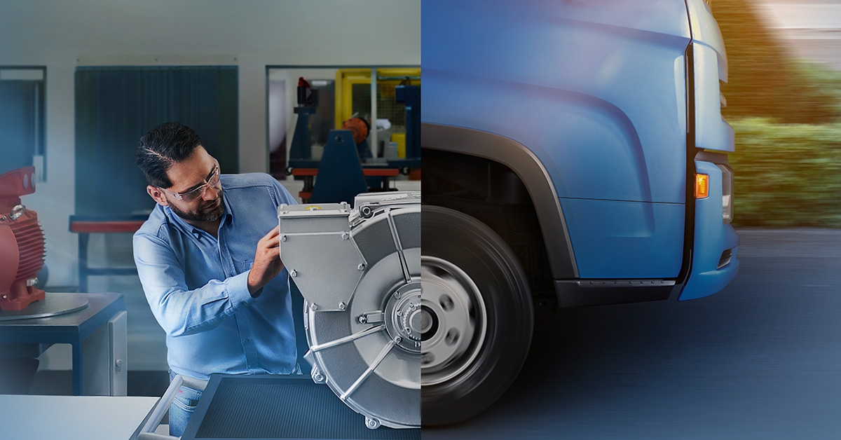 Engineer inspecting a large electric motor in a manufacturing lab, with a vehicle driving by to symbolize industrial mobility applications.