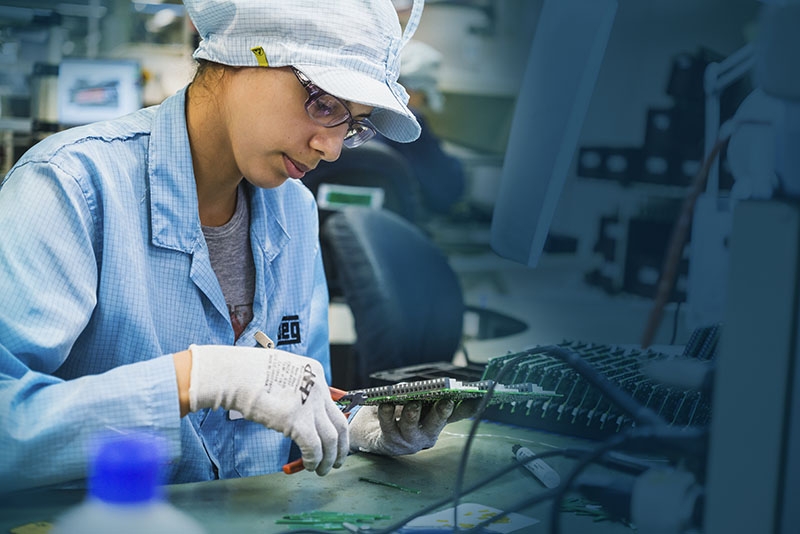 Technician assembling a circuit board in a WEG facility, showcasing precision and attention to detail in the manufacturing process of industrial drives. 