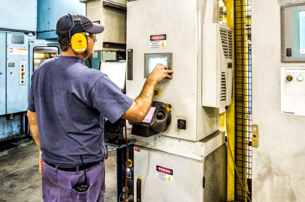 Technician operating a control panel for electric motors in an industrial automation setting.