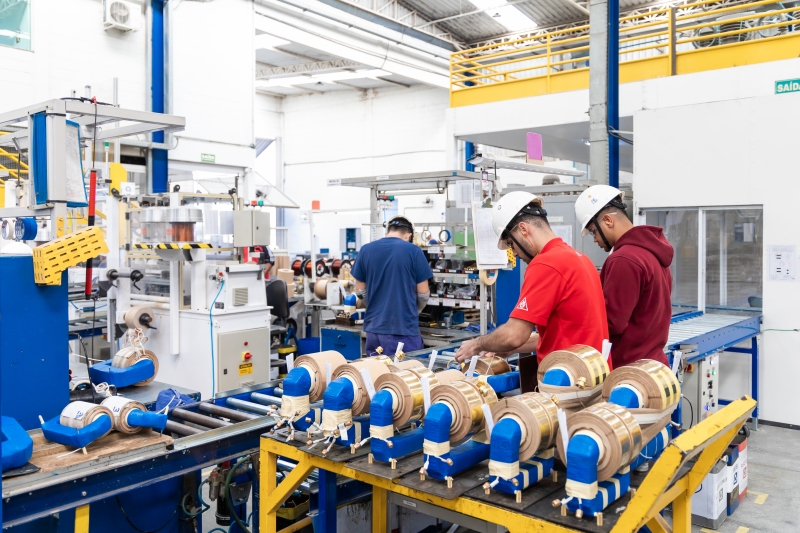 Technicians working on electric motor coils in a modern industrial automation facility.