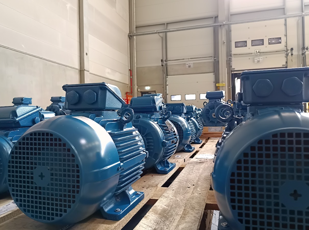 Multiple WEG W22 electric motors displayed on pallets inside an industrial warehouse, ready for deployment.