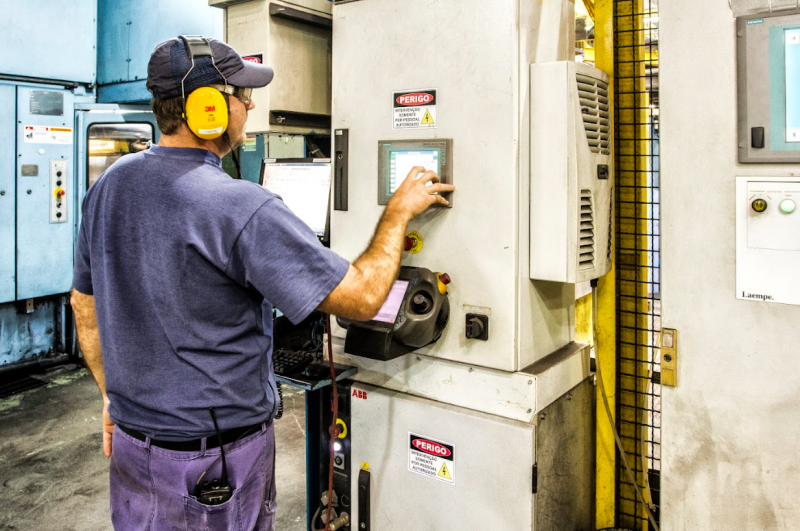 Technician operating a control panel for electric motors in an industrial automation setting.