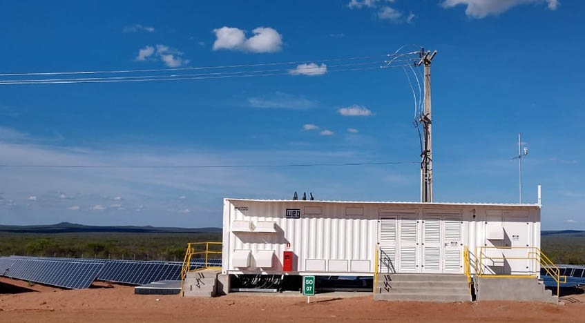 Power station will power lines coming out of top, in front of field of solar panels.